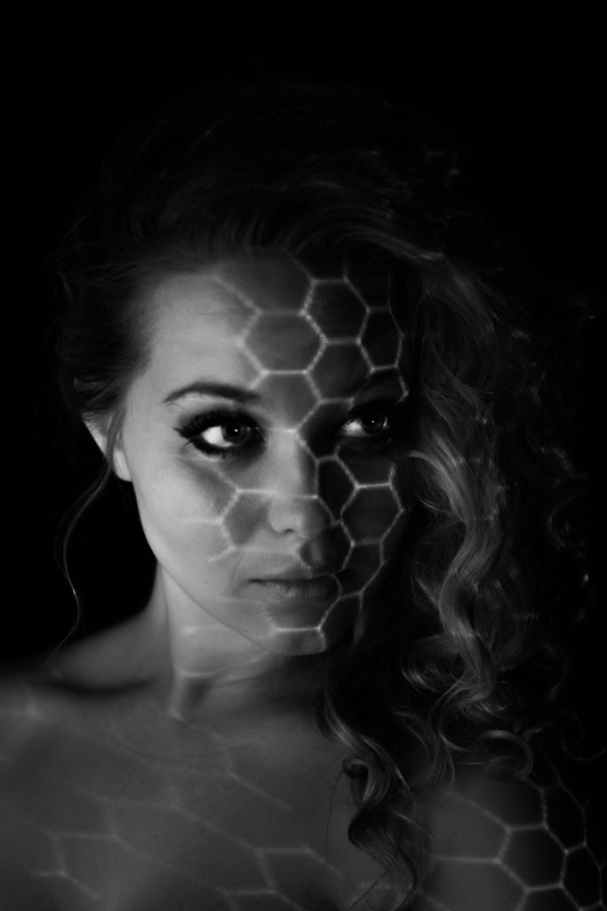 Black-and-white portrait of a woman with a honeycomb pattern of light projected across her face.