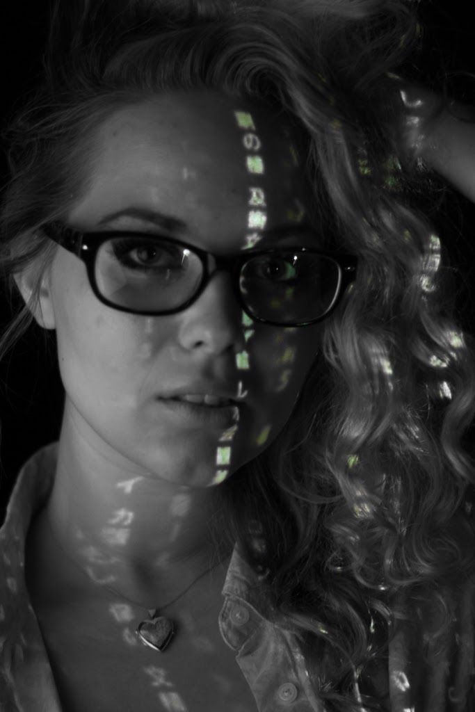 A woman in glasses with a vertical strip of projected light dividing her face.
