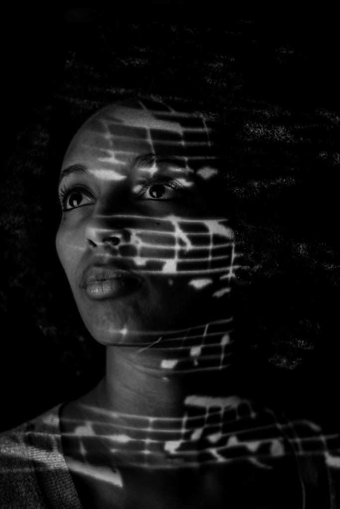 A woman gazing upward with lines of sheet music projected across her face.