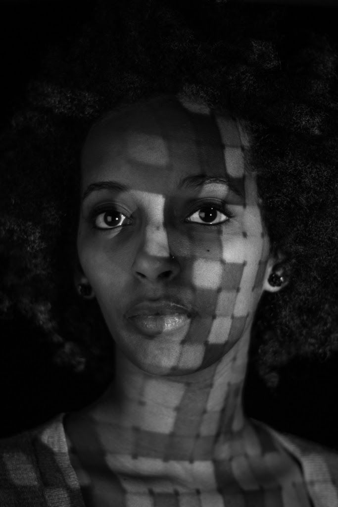 A woman facing the camera through a projected grid of soft squares.