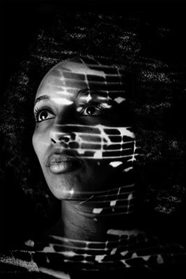 Black and white photo of Rachel with music projected onto her
	          face